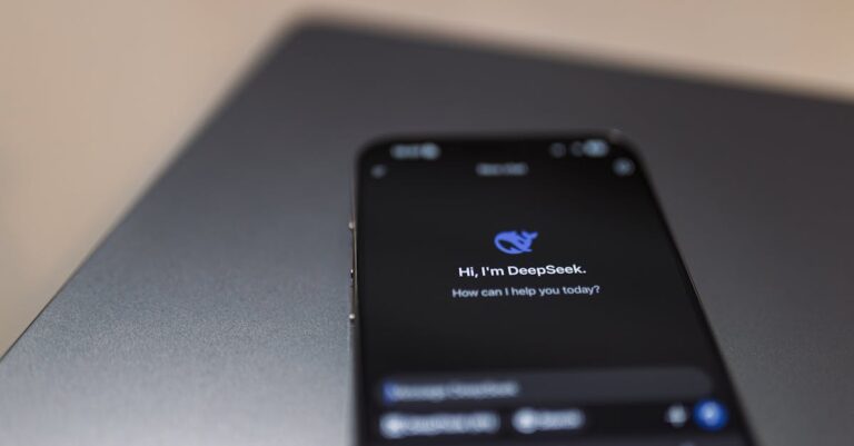 Close-up of a smartphone with AI assistant interface on screen over a laptop.