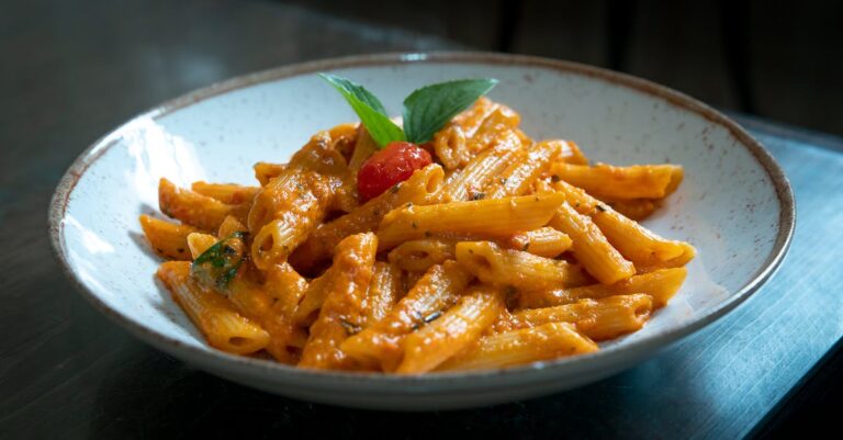 Penne pasta with rich tomato and basil sauce served in a rustic bowl.
